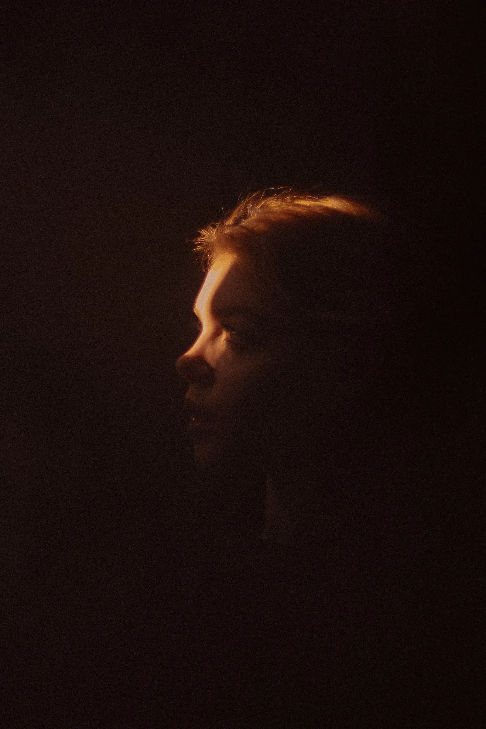 A woman's profile in low light against a dark background